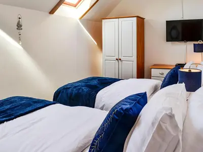 a bedroom with two beds and a tv on the wall at Hammy's Cottage in Drummore