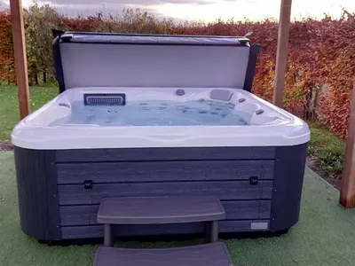a jacuzzi tub with a stool in a yard at Rowan Muir in Springside