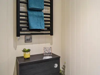 a bathroom with a black dresser with blue towels at The Seaview Snug in Whithorn