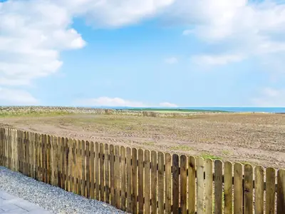 a wooden fence in front of a field at The Seaview Snug in Whithorn