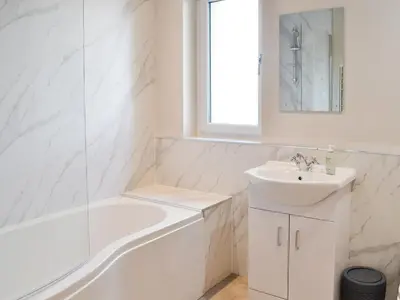 a white bathroom with a sink and a bath tub at The Byre in Castle Douglas