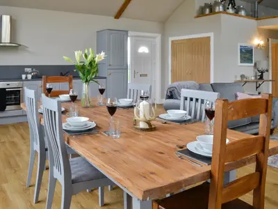 a dining room table and chairs with wine glasses on it at The Byre in Castle Douglas