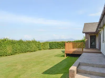 a backyard with a wooden bench and a lawn at High Mains in Winscales