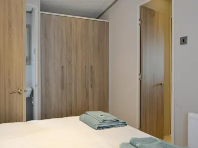 a bedroom with a bed and wooden cabinets at Tranquil Lodge - Uk35277 in Brigham