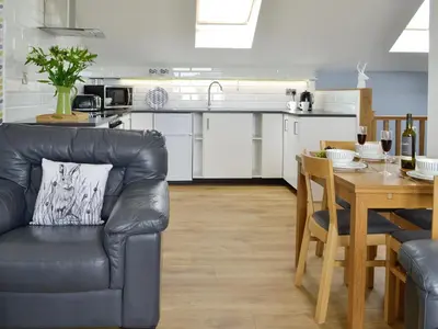 a kitchen and dining room with a leather couch and a table at Gin Case in Templand