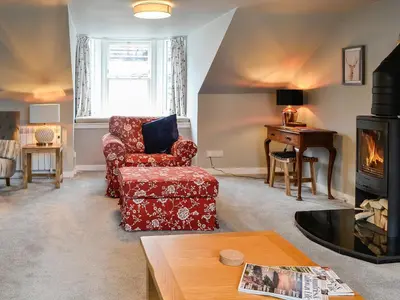 a living room with a chair and a fireplace at The Old Toll House in Portpatrick