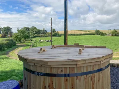 a wooden barrel sitting on top of a field at Curlew Cottage in Dinwoodie Mains