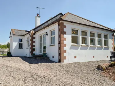 a detached house with a gravel driveway at Curlew Cottage in Dinwoodie Mains