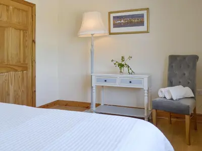 a bedroom with a bed and a table and a chair at Curlew Cottage in Dinwoodie Mains