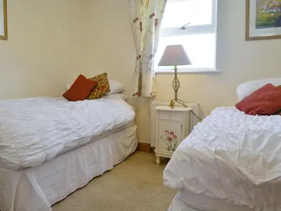 a bedroom with two beds and a window at Curlew Cottage in Dinwoodie Mains