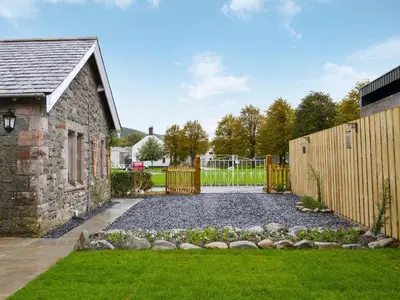 a garden with a stone building and a fence at Lealholme in Bassenthwaite