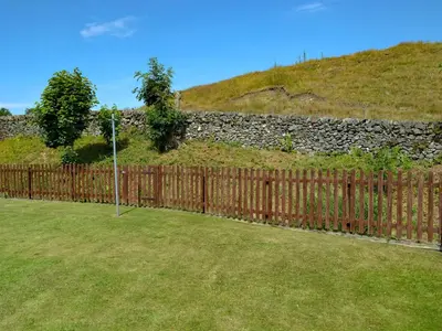 a wooden fence in front of a stone wall at Westlin in Penpont
