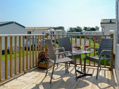 a patio with three chairs and a table on a deck at Loch View in Kirkcolm