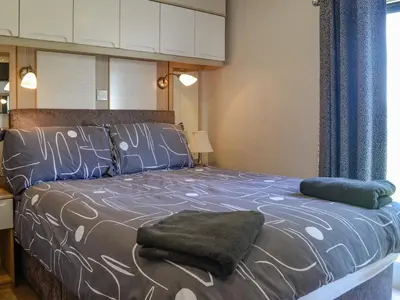 a bedroom with a bed with blue and white sheets at Loch View in Kirkcolm