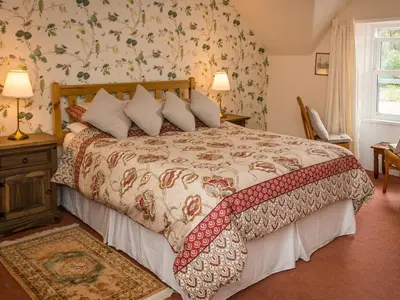 a bedroom with a large bed with a floral wallpaper at Uk35716 - North Cottage in Teviothead