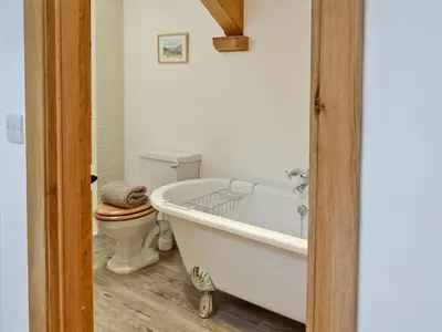 a bathroom with a white tub and a toilet at The Barn in Greystoke