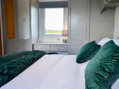 a bedroom with a bed with green pillows and a window at The Seaview Retreat - Uk35883 in Broughton Mains