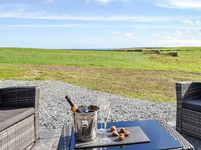 a table with wine glasses and a bucket on a patio at The Seaview Retreat - Uk35883 in Broughton Mains
