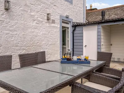 a patio with a glass table and chairs at Erriff At Caelaverock in Glencaple