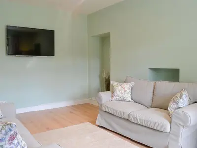 a living room with a couch and a flat screen tv at Lime Tree Cottage in Drumpark