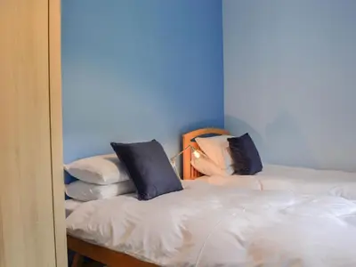 a blue room with two beds with pillows on them at Lime Tree Cottage in Drumpark