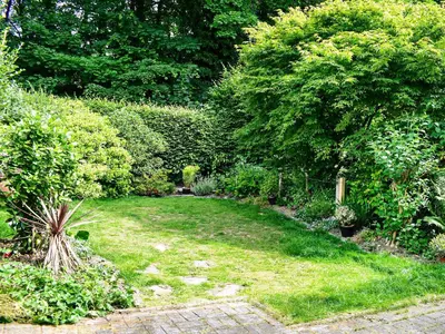a garden with green grass and trees and bushes at Jane Eyre Cottage in Keswick