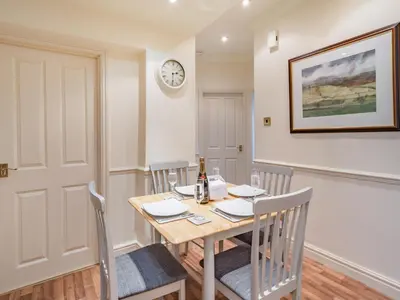 a dining room with a table and chairs and a clock at Mell Fell in Watermillock