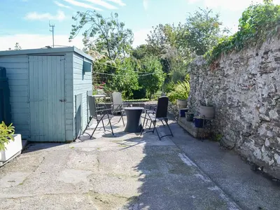 a patio with chairs and a building next to a wall at Oor Wee Hoose in Whithorn