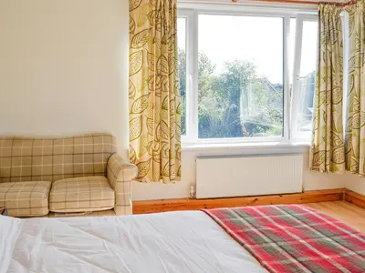 a bedroom with a couch and a large window at Oor Wee Hoose in Whithorn