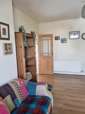 a living room with a bed and a wooden floor at West View Cottage in Seaside Village of Allonby Cumbria in Allonby