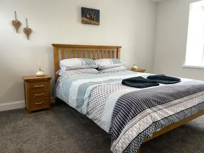 a bedroom with a bed with a wooden headboard and pillows at Galloway Farmstay Claunch in Newton Stewart