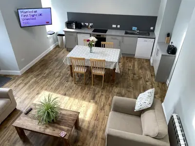 a living room with a table and a kitchen at Galloway Farmstay Claunch in Newton Stewart