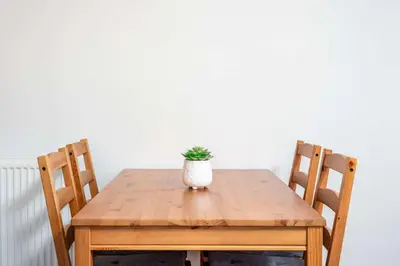 a wooden table with a plant in a vase on it at The Orchard - Donnini Apartments in Ayr