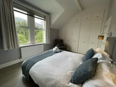 a bedroom with a large bed with a teddy bear on it at Glenderamackin Cottage in Threlkeld