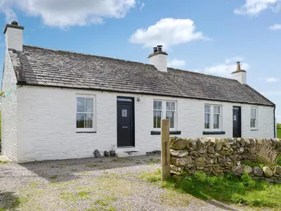 a white cottage with a stone fence in front of it at Field Cottage in Old Bridge of Urr
