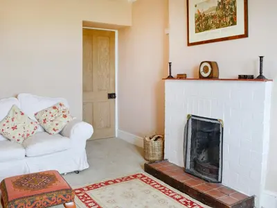 a living room with a fireplace and a white couch at Field Cottage in Old Bridge of Urr