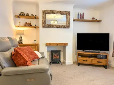 a living room with a couch and a flat screen tv at Thistle Cottage in Portpatrick