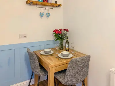 a dining room table with chairs and a vase of flowers at Thistle Cottage in Portpatrick
