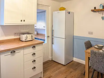 a kitchen with a white refrigerator and a table at Thistle Cottage in Portpatrick