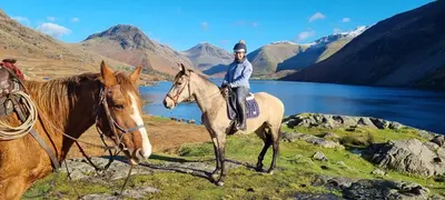 a man riding a horse on a hill next to a lake at Scafell Cottage on The Big 