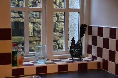 a kitchen counter with a chicken figurine on a window ledge at Rainors farm cottage in Gosforth