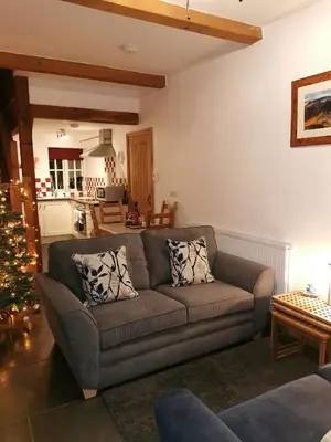 a living room with a couch and a christmas tree at Rainors farm cottage in Gosforth