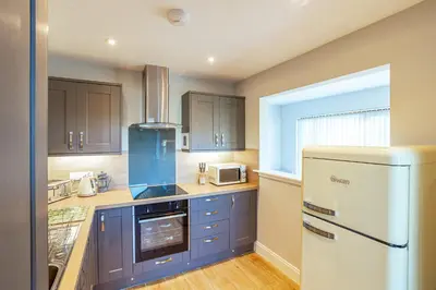 a kitchen with blue cabinets and a white refrigerator at Kestrel Lodge 7 with Hot Tub in Newton Stewart