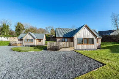 a house with a gravel driveway in front of it at Kestrel Lodge 7 with Hot Tub in Newton Stewart