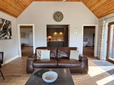 a living room with a couch and a clock on the wall at Osprey Lodge 8 with Hot Tub in Newton Stewart