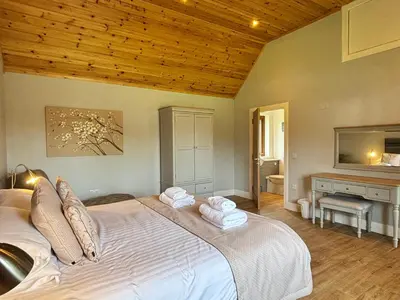 a bedroom with a large bed with towels on it at Osprey Lodge 8 with Hot Tub in Newton Stewart