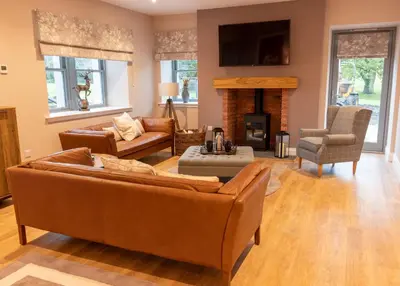 a living room with brown furniture and a fireplace at Slatehouse Cottage, Drumlanrig in Thornhill