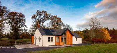 a small house with a solar roof on a field at Slatehouse Cottage, Drumlanrig in Thornhill