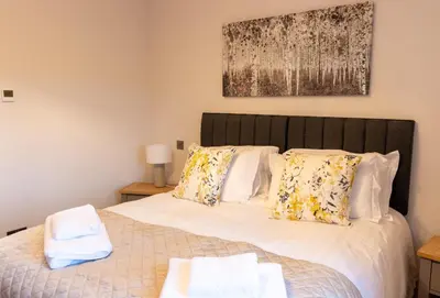 a bedroom with a bed with white sheets and pillows at Slatehouse Cottage, Drumlanrig in Thornhill