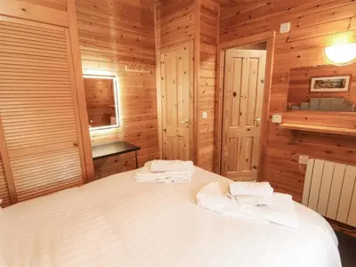 a bedroom with wooden walls and a bed with towels on it at The Fold in Keswick